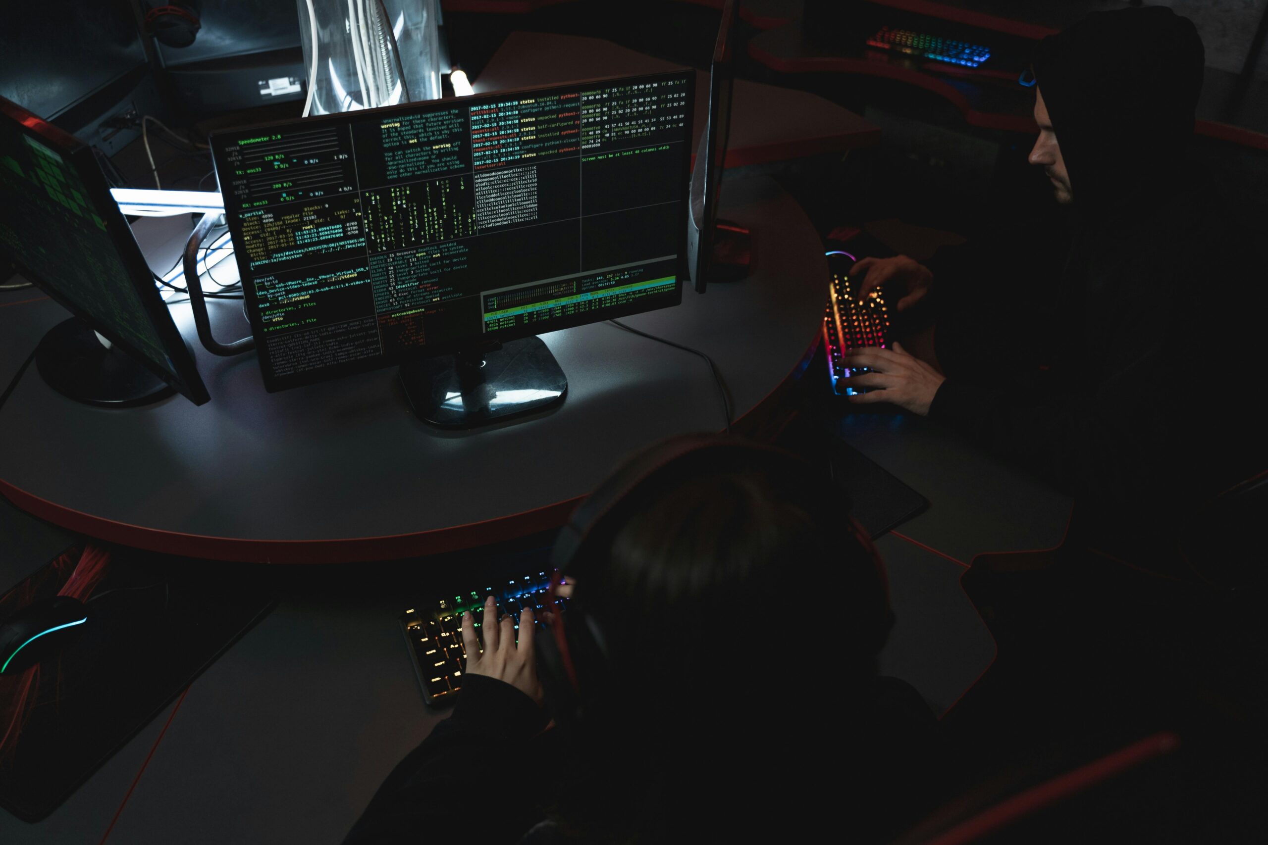 A group of people in a dark room working on computers, related to cybersecurity.